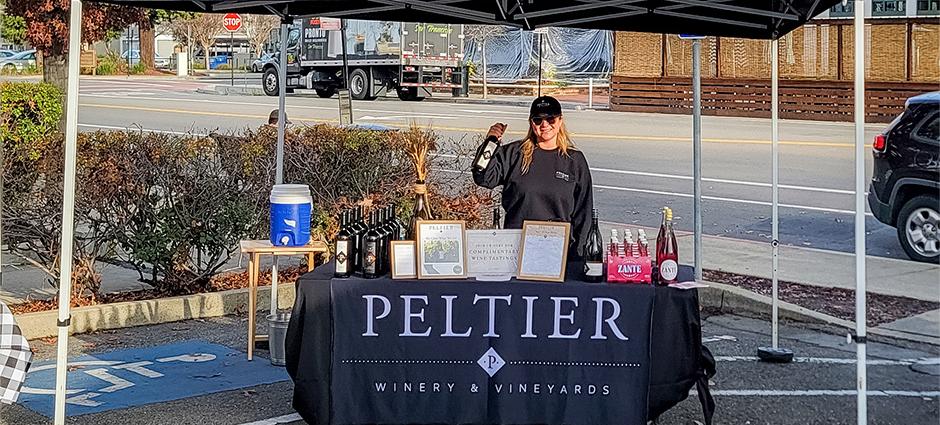 Seller holds up wine at the Peltier Wine booth at the Danville Farmers' Market