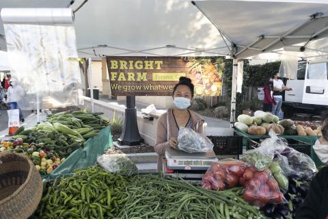 Bright Farm vendor behind table with various produce on display