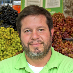 A photo of Douglas Mena, a bearded man in a green shirt