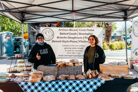 Picture of smiling producers behind table filled with goods