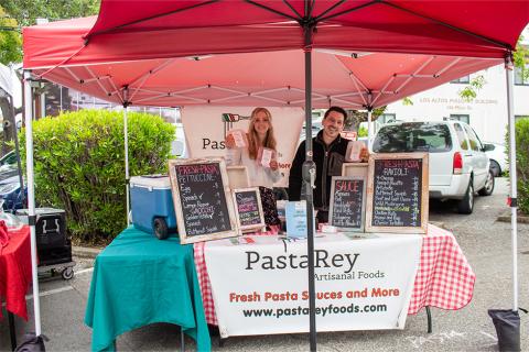 Smiling vendors at Pasta Rey holding their pastas