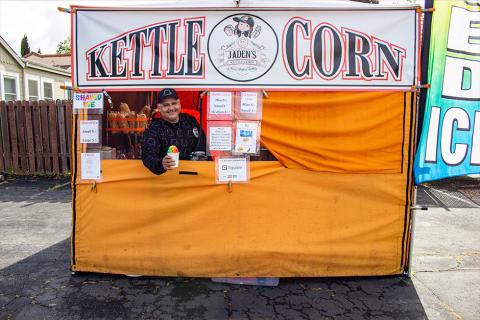 Photo of owner of Jaden's Kettle Corn handing snow cone out the window