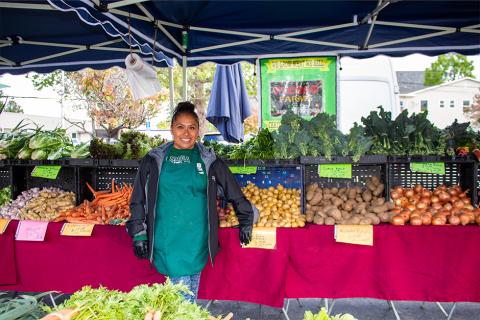 Photo of Nancy from Picoso Farm smiling in front of produce